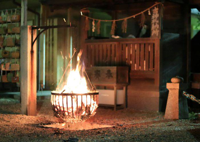 A fire sparking over a fire pit in a Japanese shrine.